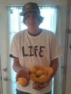 a young man holding a bowl full of fruit