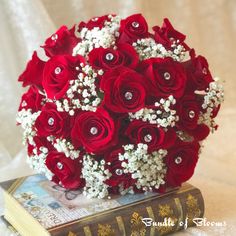 a bouquet of red roses and baby's breath sits on top of a book