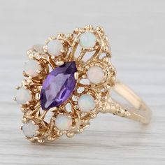 Gemstone Information: - Natural Amethyst - Carats - 0.50ct  Cut - Marquise Brilliant Color - Purple - Natural Opals - Size - 2.2 - 2.4 mm Cut - Round Cabochon Color - White with multicolor flecks Metal: 10k Yellow Gold  Weight: 3.5 Grams  Stamps: 10k Face Height: 19 mm  Rise Above Finger: 7.7 mm Band / Shank Width: 1.7 mm This ring is a size 7 1/4, but it can be resized down 2 sizes for a $20 fee or up 3 sizes for a $25 fee. If you would like your ring resized, please select the appropriate fee from the listing below in order to pay the sizing fee: https://www.etsy.com/listing/781388346/ring-sizing-service-fee Each piece is thoroughly examined and refinished as needed by our professional jewelers, graded by our in-house GIA (Gemological Institute of America) Graduate Gemologist, and inspec Antique Multi-stone Cluster Jewelry, Yellow Gold Marquise Multi-stone Jewelry, Collectible 14k Gold Gemstone Jewelry, Estate Style 14k Gold Oval Jewelry, Antique 14k Gold Cluster Jewelry, Yellow Gold Amethyst Jewelry With Center Stone, 14k Gold Purple Jewelry For Anniversary, Antique Amethyst Jewelry Stamped 14k, Purple 14k Gold Jewelry For Anniversary