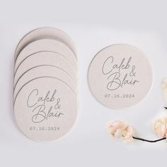 wedding coasters with the names and date printed on them, next to some flowers