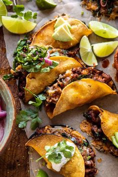 some tacos are sitting on a table with limes