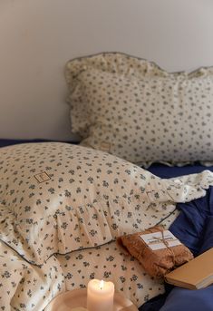 a candle is sitting on a bed with pillows and a pillow case next to it