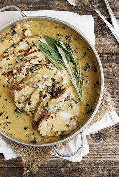 a pan filled with chicken covered in gravy and garnished with herbs