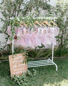 a sign that is sitting in the grass next to some clothes hanging on a rack