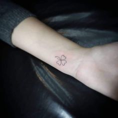 a small four leaf clover tattoo on the wrist