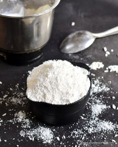 there are two spoons on the table next to some white powder in a black bowl