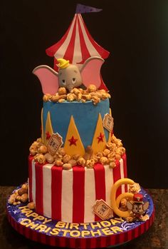 a circus themed birthday cake with an elephant in the top tier and popcorn on the bottom