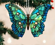 a stained glass butterfly ornament hanging from a christmas tree