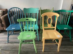 several different colored wooden chairs in a room