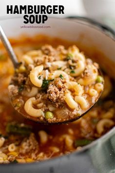 a ladle full of hamburger soup with noodles and meat in it, being held by a spoon