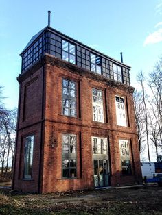 an old brick building with glass windows on the top and bottom floor, in front of some bare trees