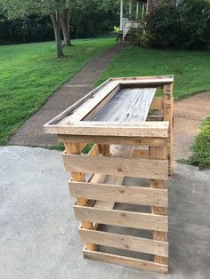 a wooden pallet sitting on top of a cement ground next to a lush green park