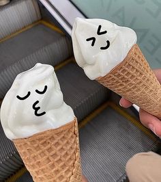 two ice cream cones with faces drawn on them sitting on an escalator next to each other