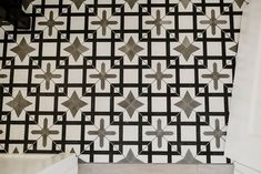 a black and white tiled wall next to a bath tub in a room with tile flooring