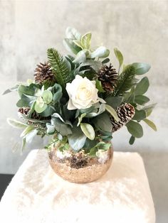 a vase filled with white flowers and greenery