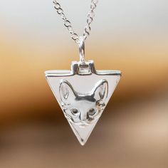 Cast from sterling silver this delightful triangular locket necklace bears the face of a cat. A hinge allows you to tuck a tiny photo or lock of hair within. Katherine Satizabal in Mexico designs and crafts the necklace which features a sterling cable chain. Sterling Silver Locket Necklace, Cat Necklace Silver, Lock Of Hair, Silver Locket Necklace, Sterling Silver Locket, Silver Locket, Locket Pendant Necklace, Silver Lockets, Cat Necklace