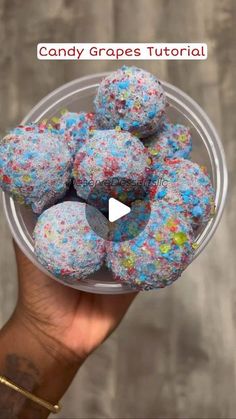 a hand holding a bowl filled with sprinkles and blue frosted donuts