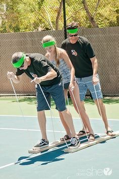 three people standing on top of a tennis court while wearing blind folded headbands