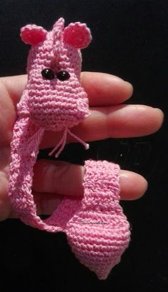 a small pink crocheted animal is held in the palm of someone's hand