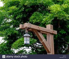 a wooden cross with a light hanging from it's side in front of some trees