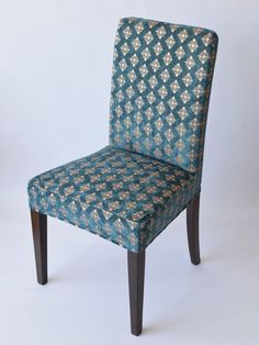 a blue and gold patterned chair against a white background with wood legs, the seat is upholstered