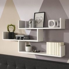 two white shelves on the wall with books and other items in front of each shelf