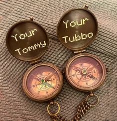 two bronze colored pocket watches with the words your tommy written on them and a key chain