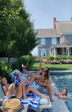 four women lounging at the edge of a swimming pool with their arms in the air