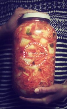 a person holding a mason jar filled with noodles and veggies in it's hands