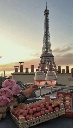 the eiffel tower is in the background with some wine glasses and fruit on display