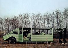 two people are sitting in the back of a green truck with trees in the background