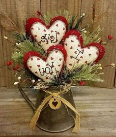 four heart - shaped ornaments in a watering can with the words i love you on them