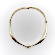 This 14k gold signed Ed Wiener necklace has a sculptural form that graces the collarbone in an elegant wave. At the center of the necklace, a pearl is nestled into a small chevron that places it perfectly along the clavicle. It is hinged with tiny ball details and seamlessly connects with a shepherd hook. The modernist design of the necklace exemplifies Ed Wiener’s ability to highlight form and function, as its lines gracefully correspond to the bone structure of the neck. The result is a gorgeous collar necklace that drapes around the neck with serene beauty.    Ed Wiener was a Modernist jeweler who started his career in 1940’s Greenwich Village and was active until the late 1980’s. He was known for his modernist forms, abstract expressionism, and Bauhaus influences. He worked mostly in s Necklace With Pearl, Gold Collar Necklace, Shepherds Hook, Gold Sign, Gold Collar, Modern Necklaces, Accessories Jewelry Necklace, Metal Necklaces, Gold Pearl