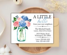 a little hello card with flowers in a mason jar on top of a wooden plate