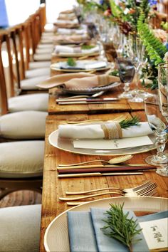 a long wooden table with place settings and napkins