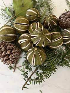 christmas ornaments and pine cones on a marble table top with greenery, leaves and branches