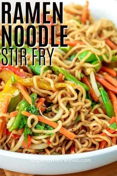 a white bowl filled with ramen noodle stir fry on top of a wooden cutting board