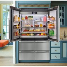 an open refrigerator in the middle of a kitchen with blue cabinets and white counter tops