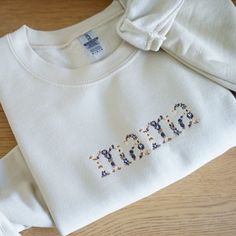 Each sweatshirt is embroidered with dark blue and neutral thread. Mama is spelled out with different flowers within the letters. Sweaters run slightly big, but if you're looking for a true oversized look size up. Inside the sweatshirt is lined with fleece. 50% cotton, 50% polyester Cream Cotton Sweatshirt With Letter Embroidery, Cream Cotton Sweatshirt For Fall, Cream Tops With Letter Embroidery For Fall, Cream Cotton Sweatshirt With Embroidered Text, Casual Cream Sweatshirt With Letter Embroidery, Cream Cotton Sweatshirt With Letter Print, Fleece Sweatshirt With Letter Embroidery For Fall, Fall Sweatshirt For Loungewear With Embroidered Text, Oversized Fall Sweatshirt With Letter Embroidery