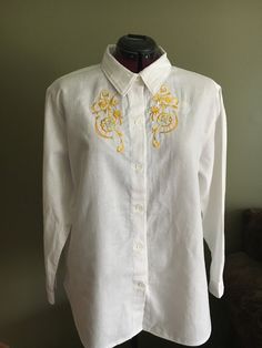 "Handmade ladies embroidered western shirt is a size extra large made in white cotton fabric.   This shirt has 3 tones premium yellow rayon embroidery thread with gold metallic thread in design.  Front button closure with white buttons that have a delicate flower design to compliment design on shirt.  Shirt measures 24\" flat from side to side, length is 14\" from underarm to hem, with 17.5\" sleeves.  Cotton has been prewashed prior to construction to minimize any shrinkage.  Made in Nova Scotia" White Long Sleeve Shirt With Machine Embroidery, Classic Embroidered Summer Shirt, Fitted White Tops With Machine Embroidery, Fitted White Top With Machine Embroidery, White Fitted Top With Machine Embroidery, Gold Long Sleeve Cotton Shirt, Summer Embroidered Gold Tops, White Cotton Blouse With Tonal Embroidery, Embroidered Gold Tops For Summer