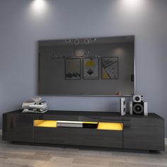 an entertainment center with two speakers and a large mirror on the wall above it is lit by yellow lights