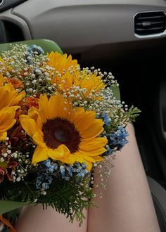 a bouquet of sunflowers sits in the passenger seat of a car, with baby's breath