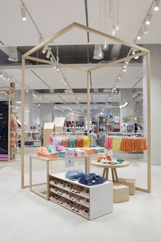 the inside of a clothing store with lots of items on display and lights hanging from the ceiling