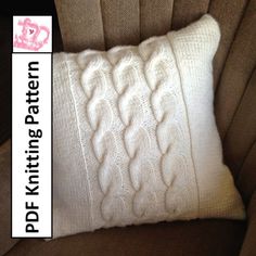 a white knitted pillow sitting on top of a brown couch