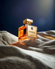 a bottle of perfume sitting on top of sand