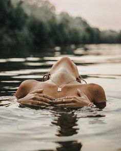 a woman floating on top of a body of water with her hands in the water