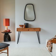 a room with a table, mirror and lamp on it's side stand in front of a white wall