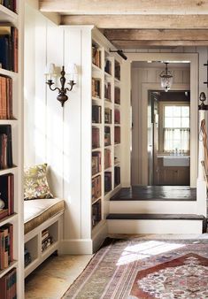 a room with many bookshelves and a rug on the floor in front of it