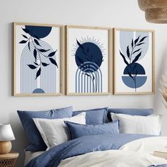 three framed art prints on the wall above a bed with blue sheets and white pillows