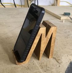 a cell phone sitting on top of a wooden stand next to a piece of wood